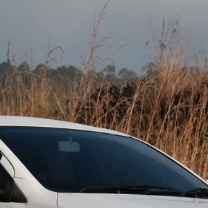 White Agya parked on a dirt road with dry grass and hills in the background.