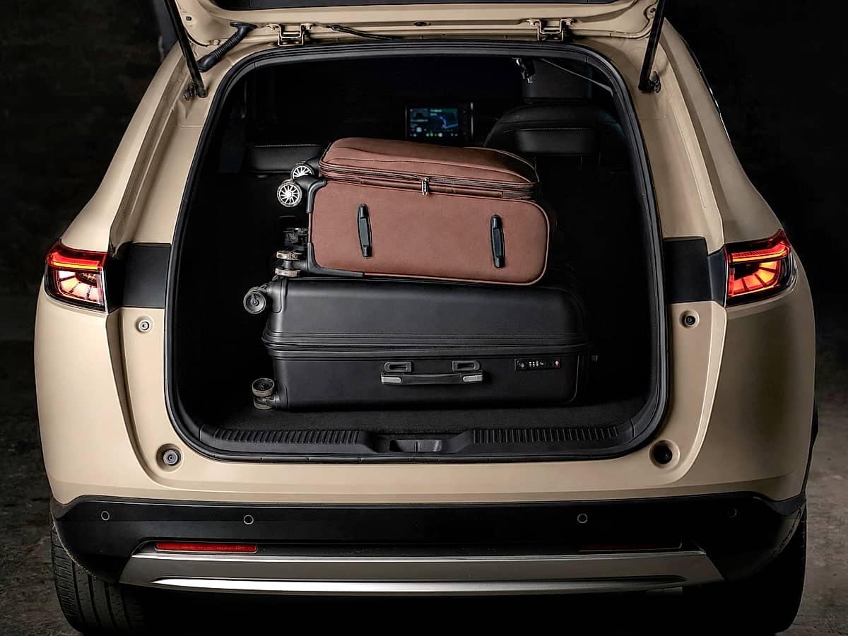 View from the rear of a beige Honda HRV with its trunk open, revealing luggage packed for a trip.