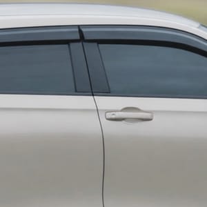 Light-colored Honda HRV crossover SUV in profile shot move quickly along a road.
