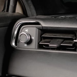 Close-up of a car's interior showing the door handle, side mirror, and dashboard air vents.