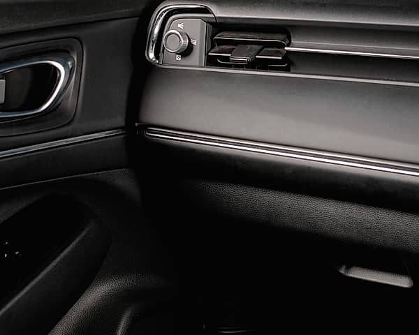 Close-up of a car's interior showing the door handle, side mirror, and dashboard air vents.