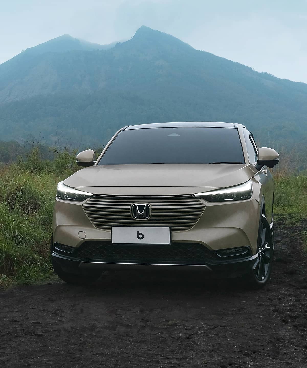 Front view of a tan Honda HR-V SUV positioned on a natural landscape with a vast mountain vista.