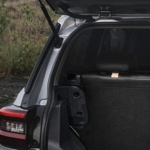 Rear view of a silver compact SUV with its trunk open, showcasing cargo space in a natural outdoor setting.