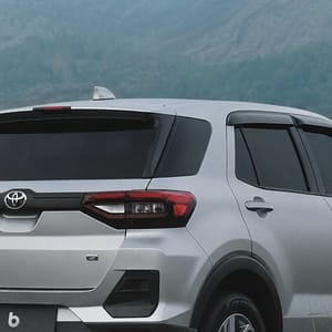 Toyota Raize positioned on a rough, earthy track amidst vibrant green foliage, with majestic mountains dominating the horizon in Bali.