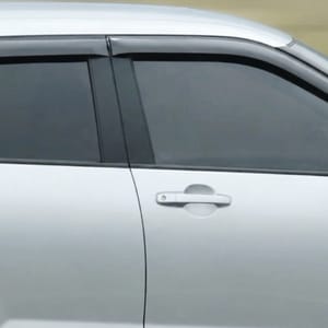 The side profile of a  silver Toyota Raize captured with a blurred natural landscape behind it.