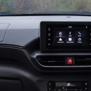Interior view of a dashboard with a touchscreen infotainment system and steering wheel.