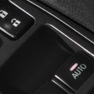 Close-up of a car's interior door panel showing electric window control buttons.