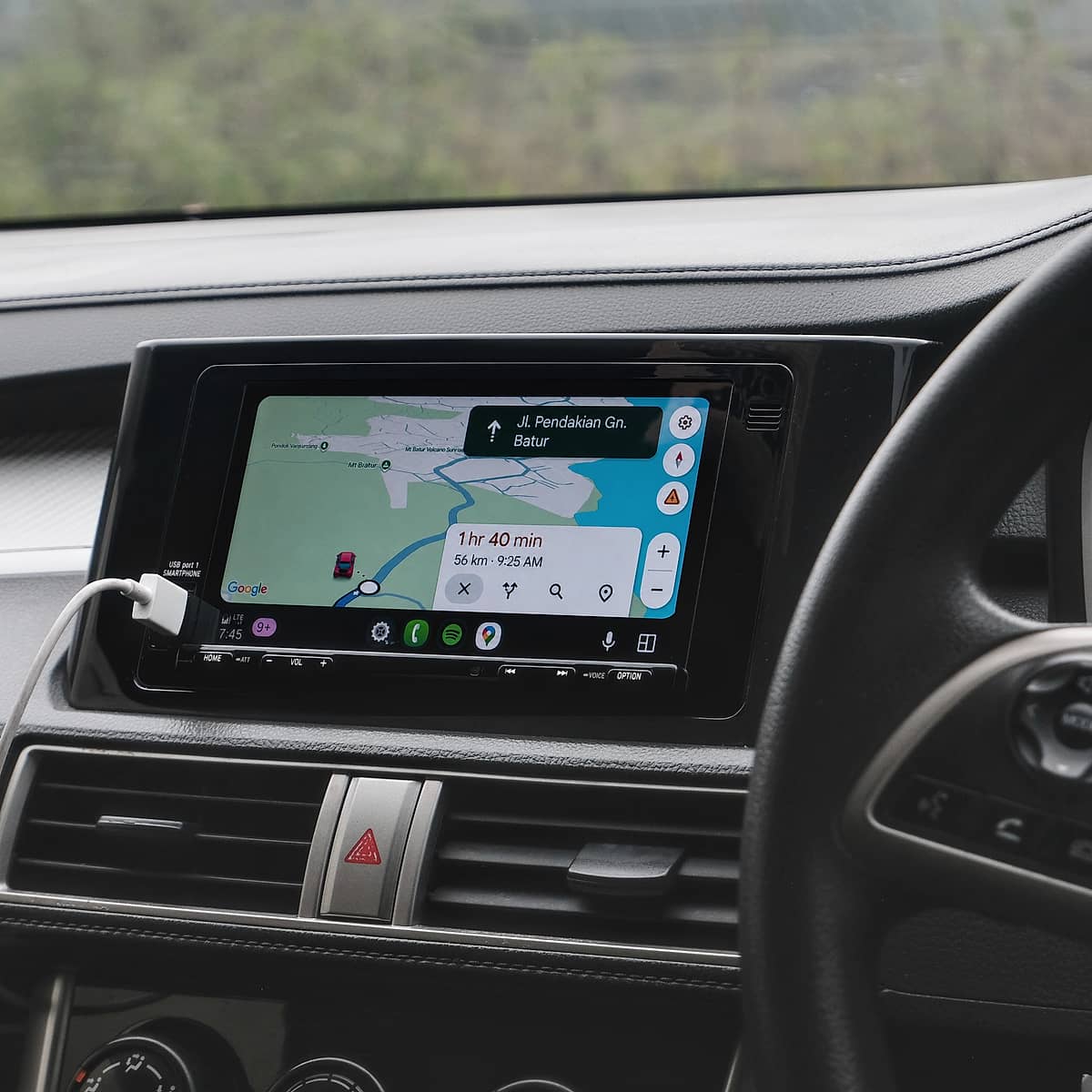 In-car entertainment system with a touchscreen showing Google Maps navigation and destination details.