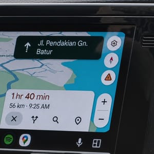 In-car entertainment system with a touchscreen showing Google Maps navigation and destination details.