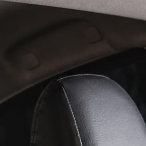 Interior view of a car's rear air conditioning vents, with black leather headrests visible in the foreground.