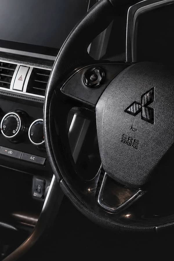 Close-up of a car's steering wheel, dashboard, and part of the infotainment screen visible.
