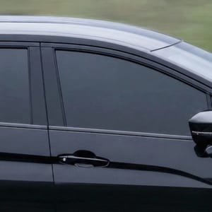 Black Mitsubishi Xpander MPV driving on a asphalt road with green, hilly background.