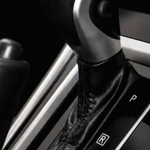 View of the central console in a car, featuring the automatic gear selector, parking brake, and part of the steering wheel.